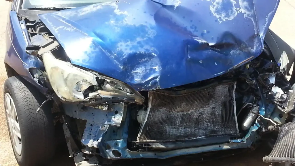 Close-up of front-end damage on a blue car after a collision